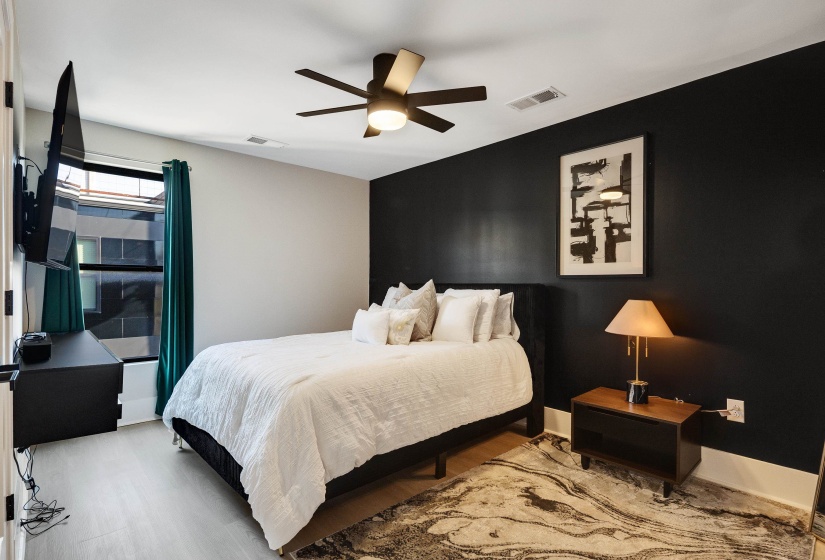 Bedroom with an accent wall, wood finished floors, and ceiling fan