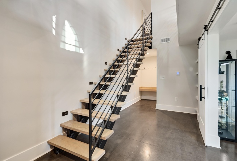 Stairway with a barn door, concrete floors, and a high ceiling