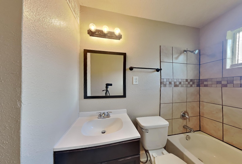 Full bath with vanity, tub / shower combination, and a textured wall