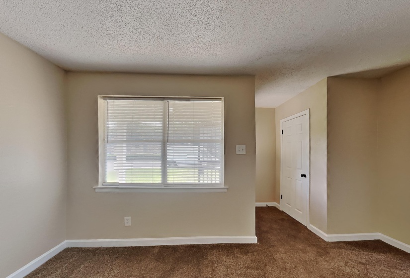 Empty room with dark colored carpet and a textured ceiling
