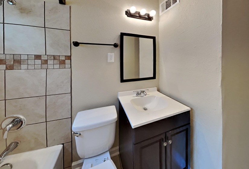 Bathroom featuring vanity, a textured wall, and bathtub / shower combination