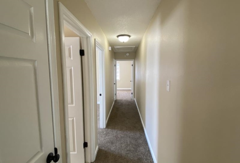 Corridor featuring dark colored carpet and a textured ceiling