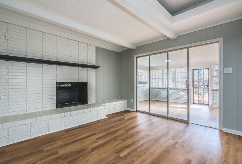 Unfurnished den featuring wood finished floors, beam ceiling, a fireplace, and wood walls