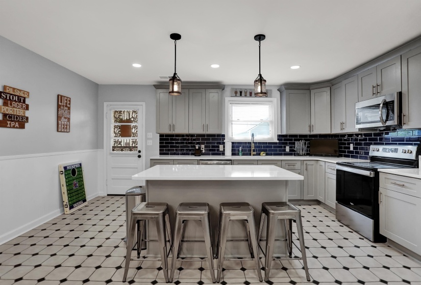 Kitchen featuring light countertops, a breakfast bar, stainless steel appliances, gray cabinets, and light floors