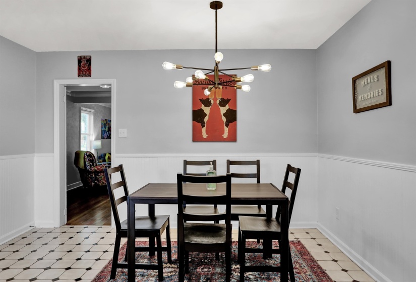 Dining room with a wainscoted wall, a chandelier, and light floors