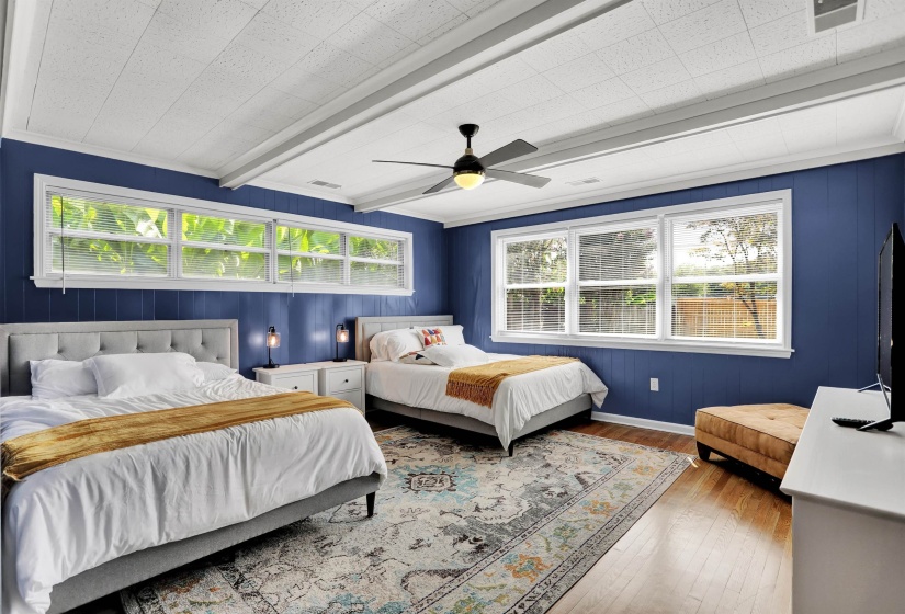 Bedroom with wood-type flooring, ceiling fan, visible vents, and beamed ceiling