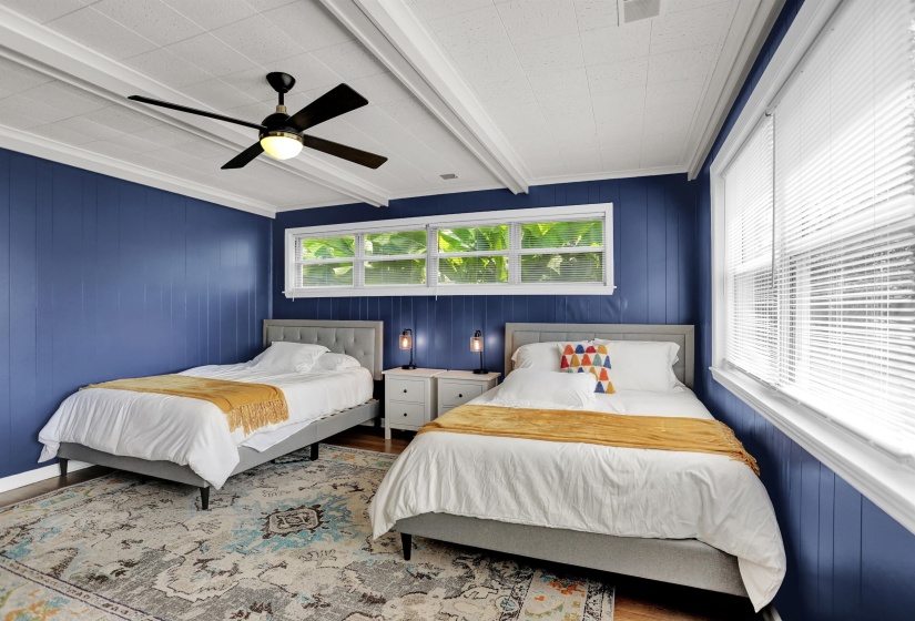 Bedroom featuring wood finished floors, ornamental molding, ceiling fan, and multiple windows