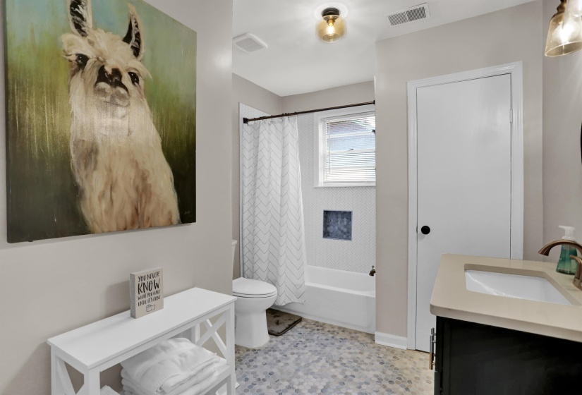 Bathroom featuring visible vents, toilet, vanity, and shower / bath combination with curtain