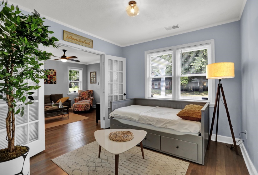 Bedroom featuring dark wood-style flooring, baseboards, ornamental molding, and visible vents