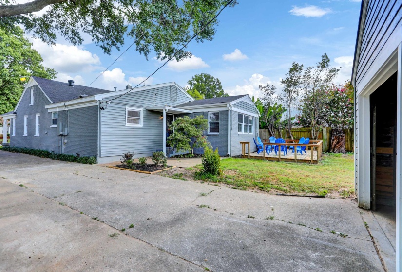 Back of house with brick siding, fence, a wooden deck, and a lawn