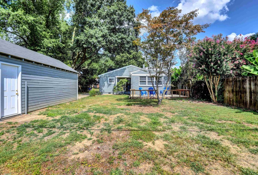 View of yard with a wooden deck, fence, and an outbuilding