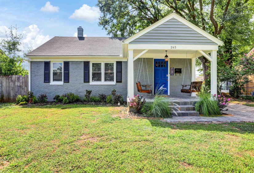 View of front facade featuring a shingled roof, covered porch, a front lawn, and brick siding
