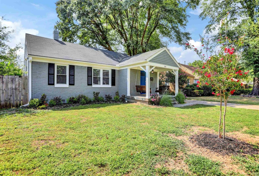 Ranch-style home with covered porch, fence, a front lawn, brick siding, and a chimney