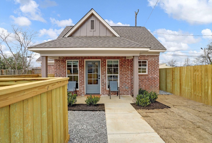 Exterior space featuring brick siding, fence, and a shingled roof