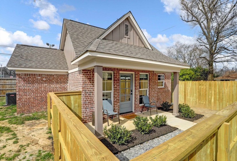 Exterior space with central AC, board and batten siding, fence, brick siding, and roof with shingles