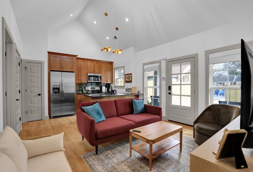 Living room featuring light wood-style flooring, high vaulted ceiling, visible vents, and recessed lighting
