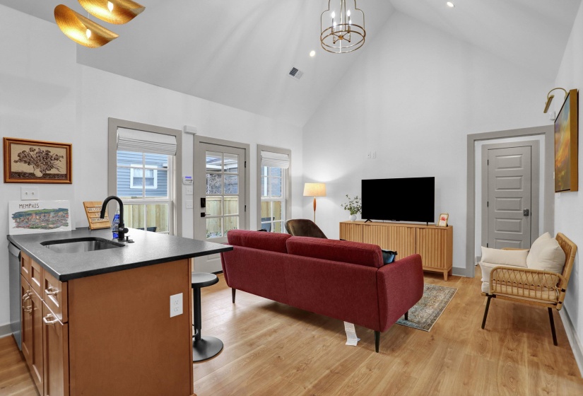 Living room featuring high vaulted ceiling, a notable chandelier, light wood-style flooring, and visible vents