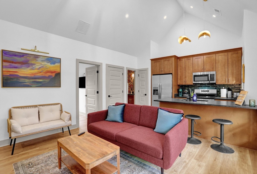 Living room with visible vents, light wood-style flooring, high vaulted ceiling, and recessed lighting
