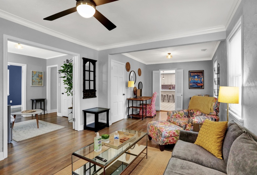 Living area featuring ceiling fan, baseboards, ornamental molding, and wood finished floors