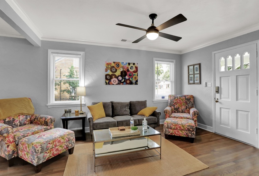Living area with visible vents, ceiling fan, crown molding, and wood finished floors
