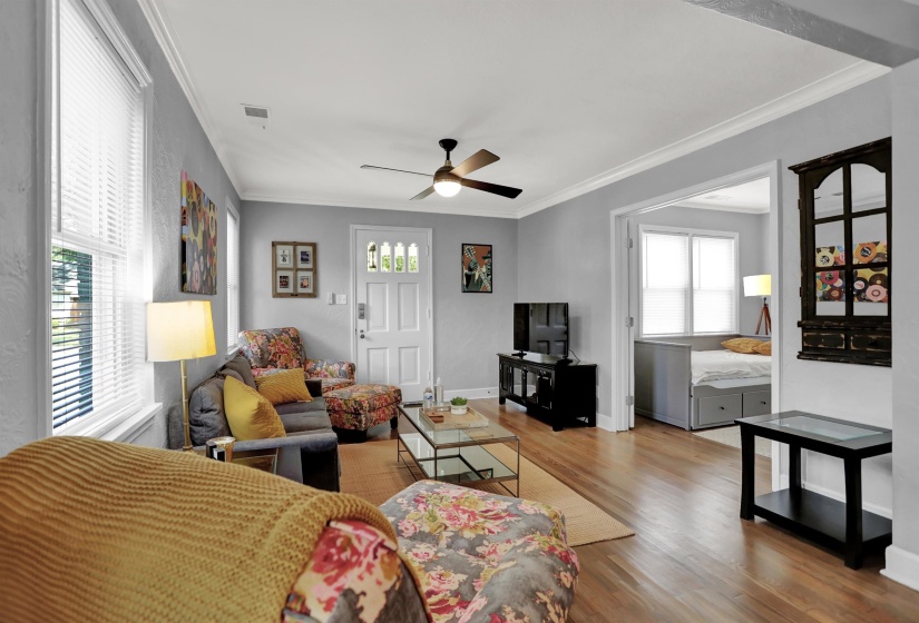 Living area featuring visible vents, a ceiling fan, ornamental molding, and wood finished floors
