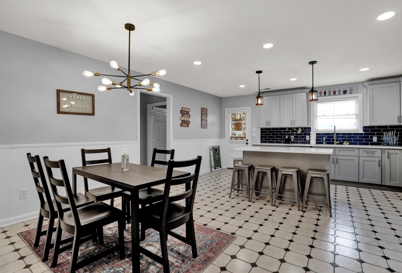 Dining room featuring a chandelier, light floors, recessed lighting, and a wainscoted wall