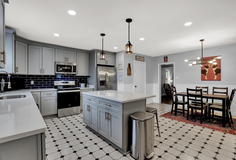 Kitchen featuring light floors, light countertops, a sink, stainless steel appliances, and gray cabinetry