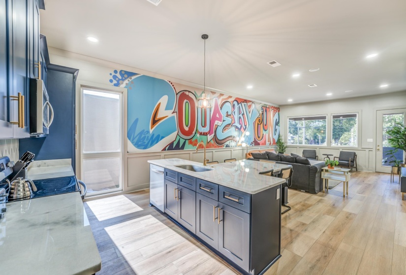 Kitchen featuring stainless steel dishwasher, a sink, light wood finished floors, light stone countertops, and visible vents