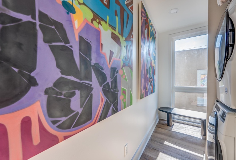 Hallway featuring stacked washer / drying machine, wood finished floors, and baseboards
