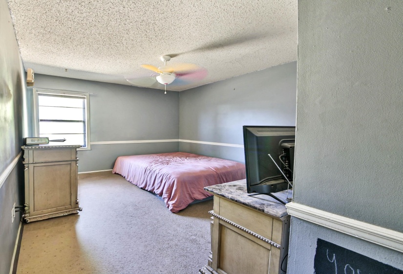 Bedroom with light colored carpet, a ceiling fan, and a textured ceiling