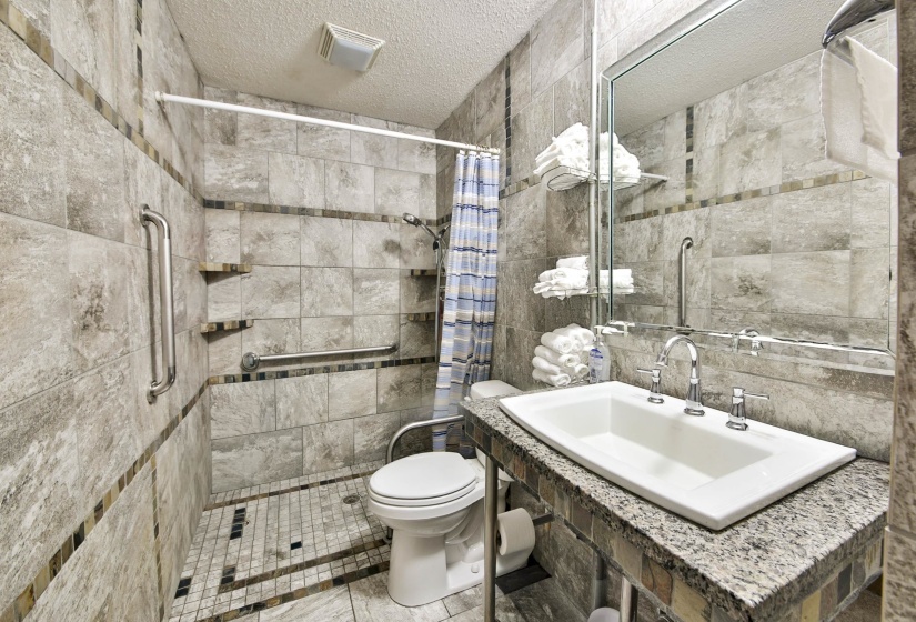 Full bathroom featuring a textured ceiling, tile walls, and a stall shower