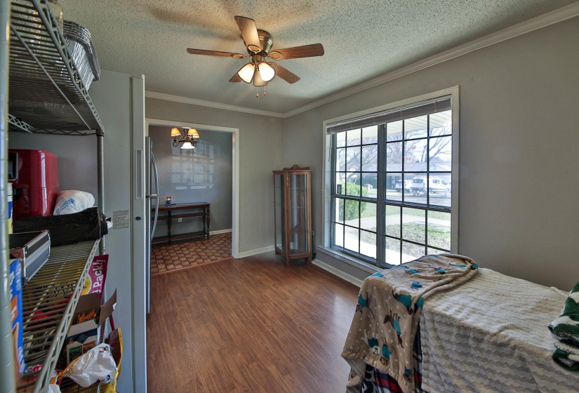 Bedroom with a textured ceiling, dark wood-style flooring, ceiling fan, ornamental molding, and freestanding refrigerator