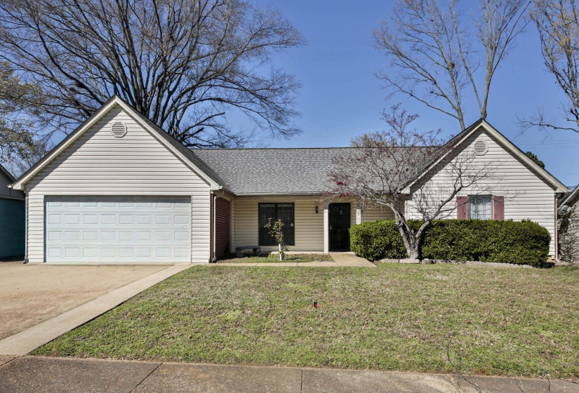 Single story home featuring a front lawn, driveway, a porch, an attached garage, and a shingled roof