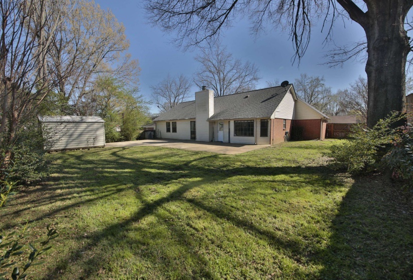 Back of property with a patio, brick siding, a shed, a chimney, and roof with shingles
