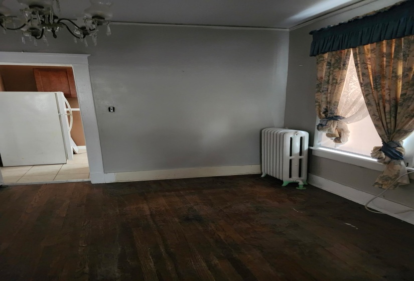 Empty room with radiator heating unit, wood finished floors, and a chandelier