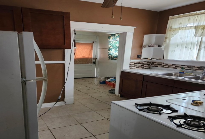 Kitchen featuring white appliances, dark brown cabinets, light tile patterned flooring, light countertops, and decorative backsplash