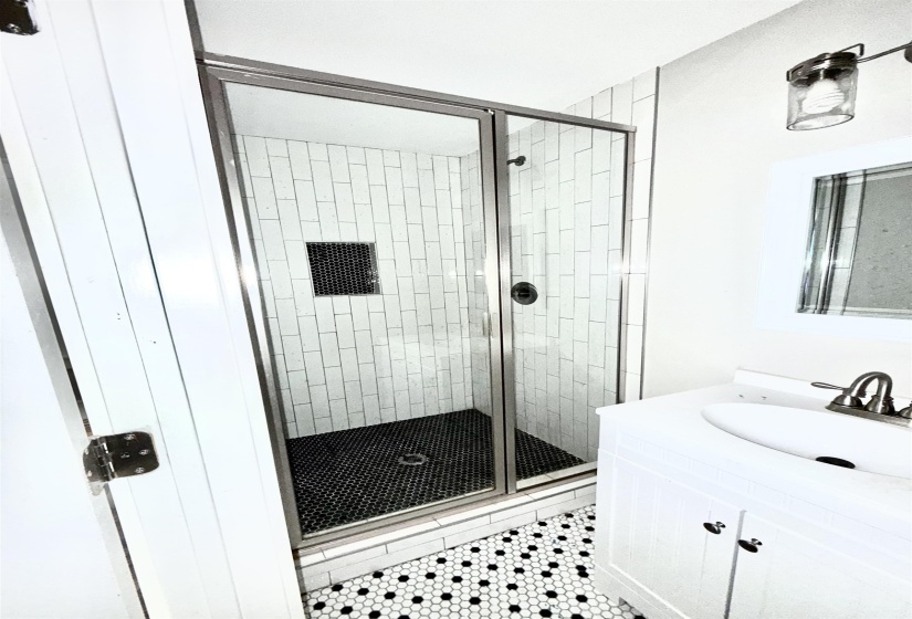 Full bathroom featuring a stall shower, vanity, and light tile patterned flooring