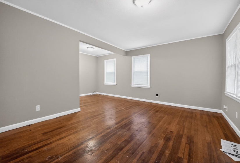 Empty room featuring dark wood-style floors and crown molding