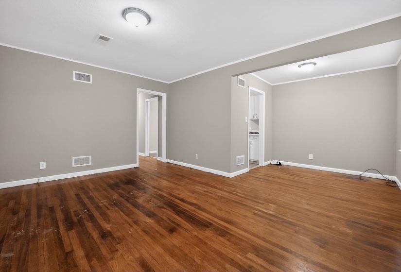 Empty room featuring dark wood finished floors and ornamental molding