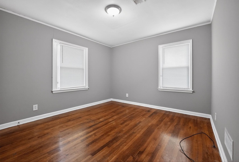 Unfurnished room with ornamental molding and dark wood-type flooring