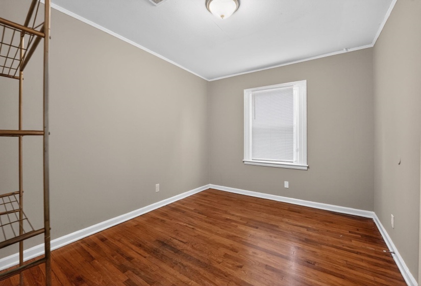 Spare room with ornamental molding and dark wood-style floors