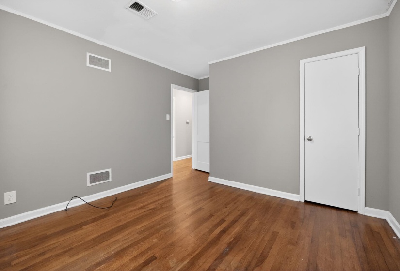 Unfurnished bedroom featuring crown molding and dark wood-style floors