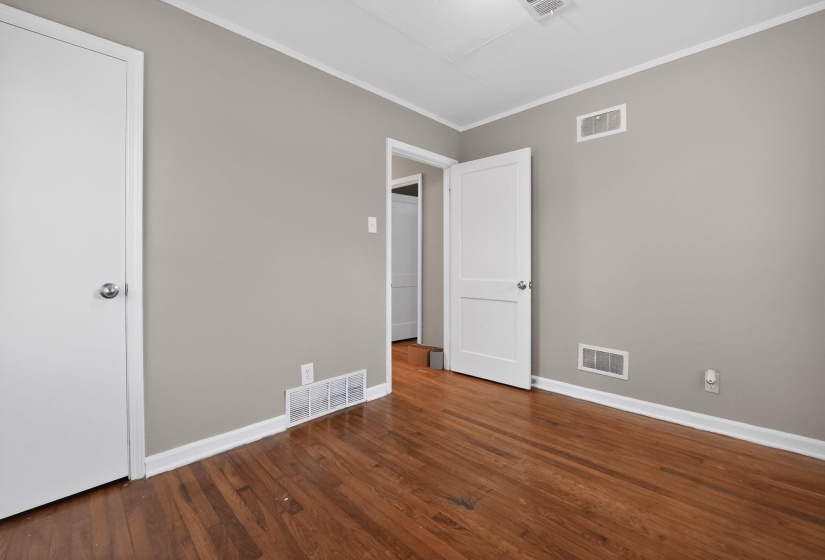 Spare room with ornamental molding and dark wood-type flooring