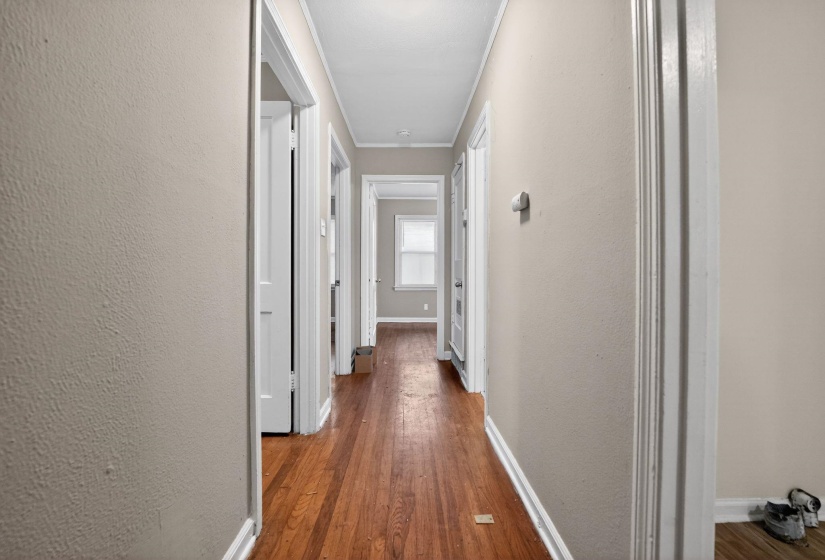 Corridor featuring a textured wall, wood finished floors, and crown molding