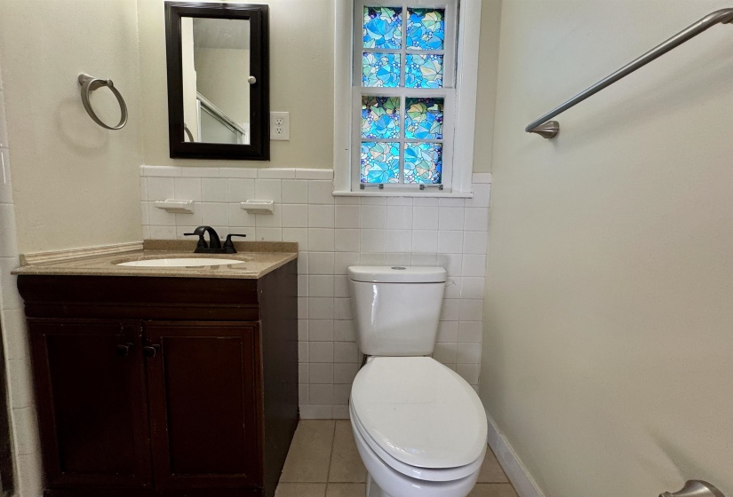 Half bath featuring vanity, tile walls, light tile patterned floors, and wainscoting