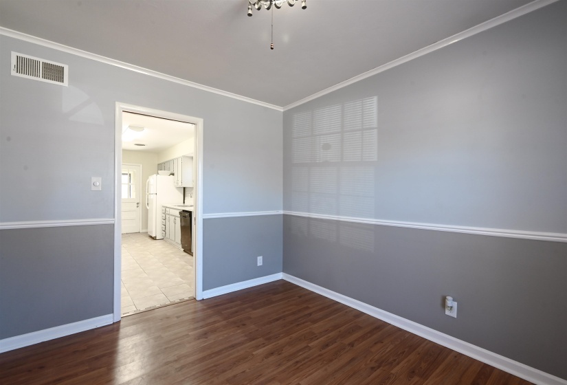 Spare room featuring ornamental molding and dark wood-type flooring