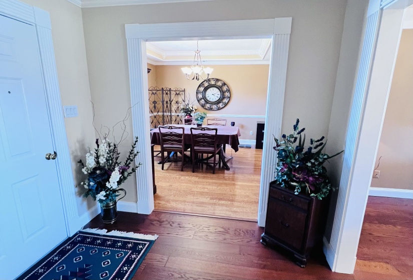 Foyer with dark wood-style flooring, crown molding, and hanging lights