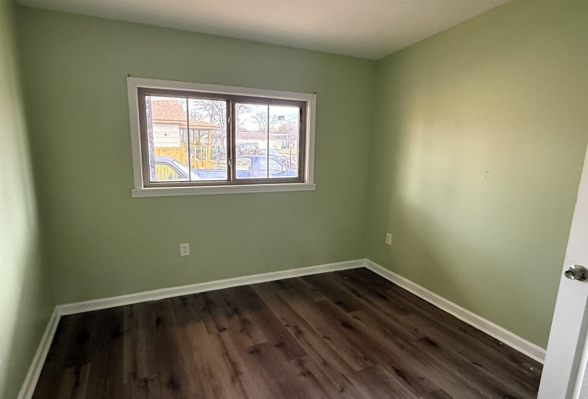 Spare room with baseboards and dark wood-type flooring