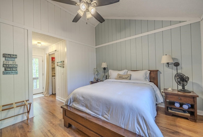 Vaulted ceiling bedroom featuring wood-finish flooring and board and batten wall paneling