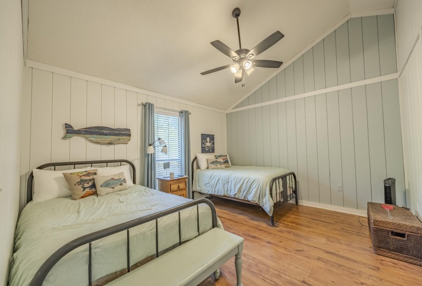 Room featuring wood-finish flooring, vertical paneling, and an angled ceiling